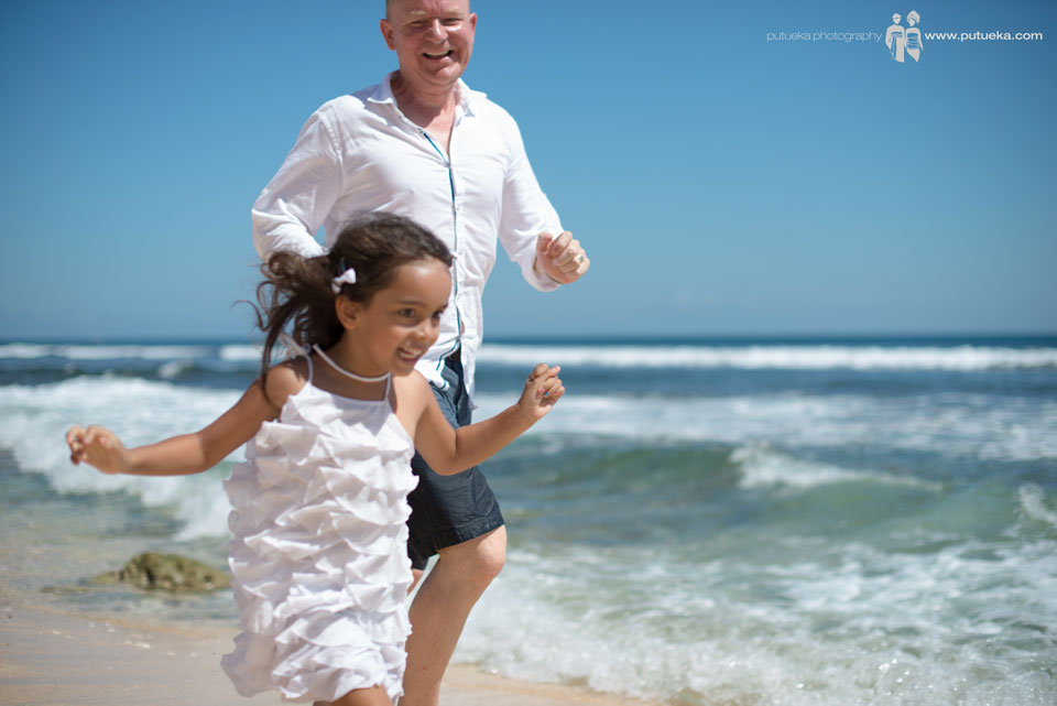 Running along the shoreline with big smile and laugh on family photography session