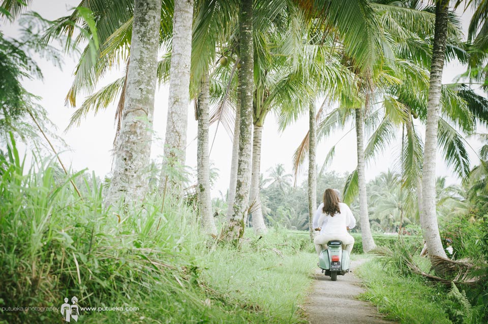Riding scooter under coconut trees on family vacation photography session in Ubud Bali