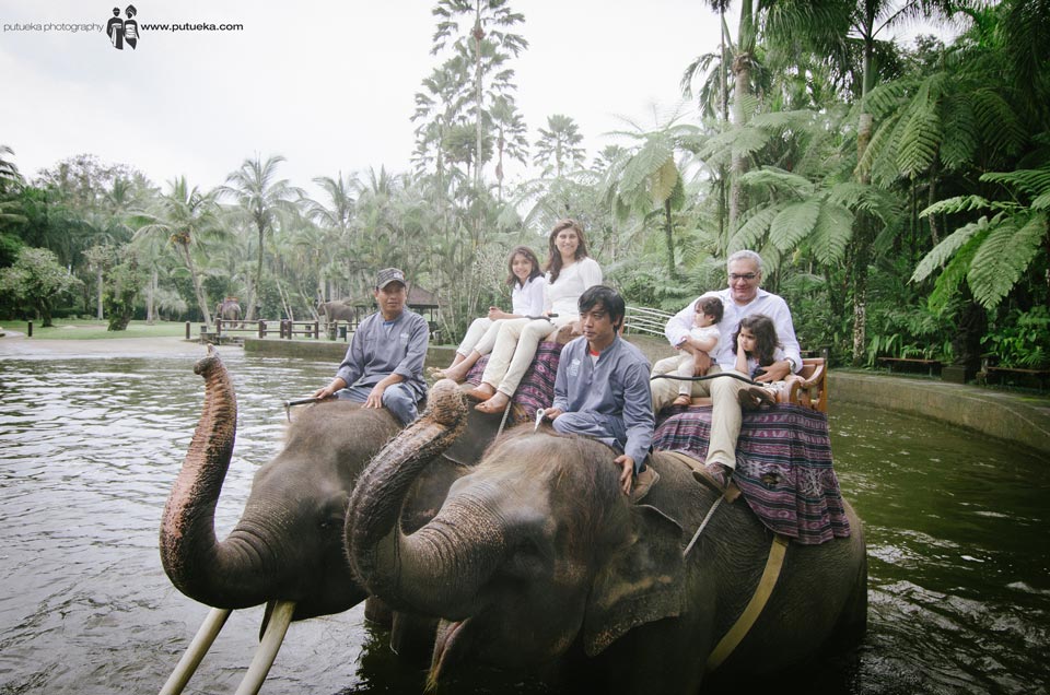Whole family riding elephants in the middle of the pond