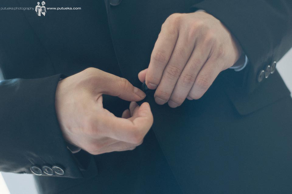 Groom button his black wedding suit